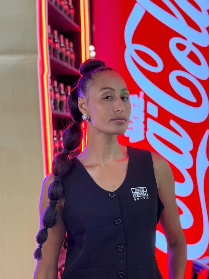 Joelma em frente a um letreiro luminoso da Coca-Cola